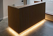 Efektowna lada recepcyjna z lamelami i podświetleniem LED z przeznaczeniem do salonu wizażu w Toruniu.